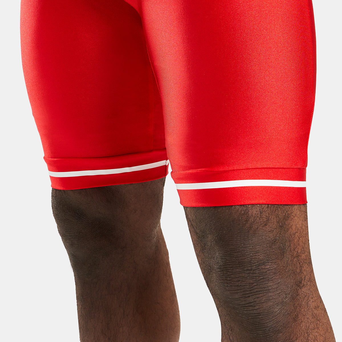 This image displays a pair of vibrant red athletic shorts featuring a sleek design with white accent stripes at the hem highlighting a snug fit and a modern athletic aesthetic