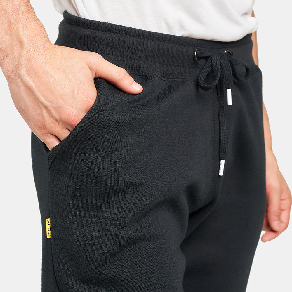 A close-up view of a person wearing dark jogger pants with a hand in the pocket showcasing a casual and stylish look