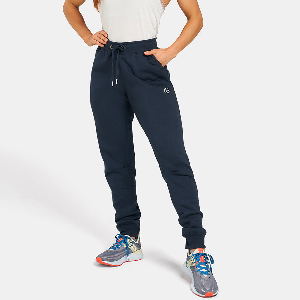 A woman stands confidently in dark sweatpants and athletic shoes showcasing a laid-back yet stylish look