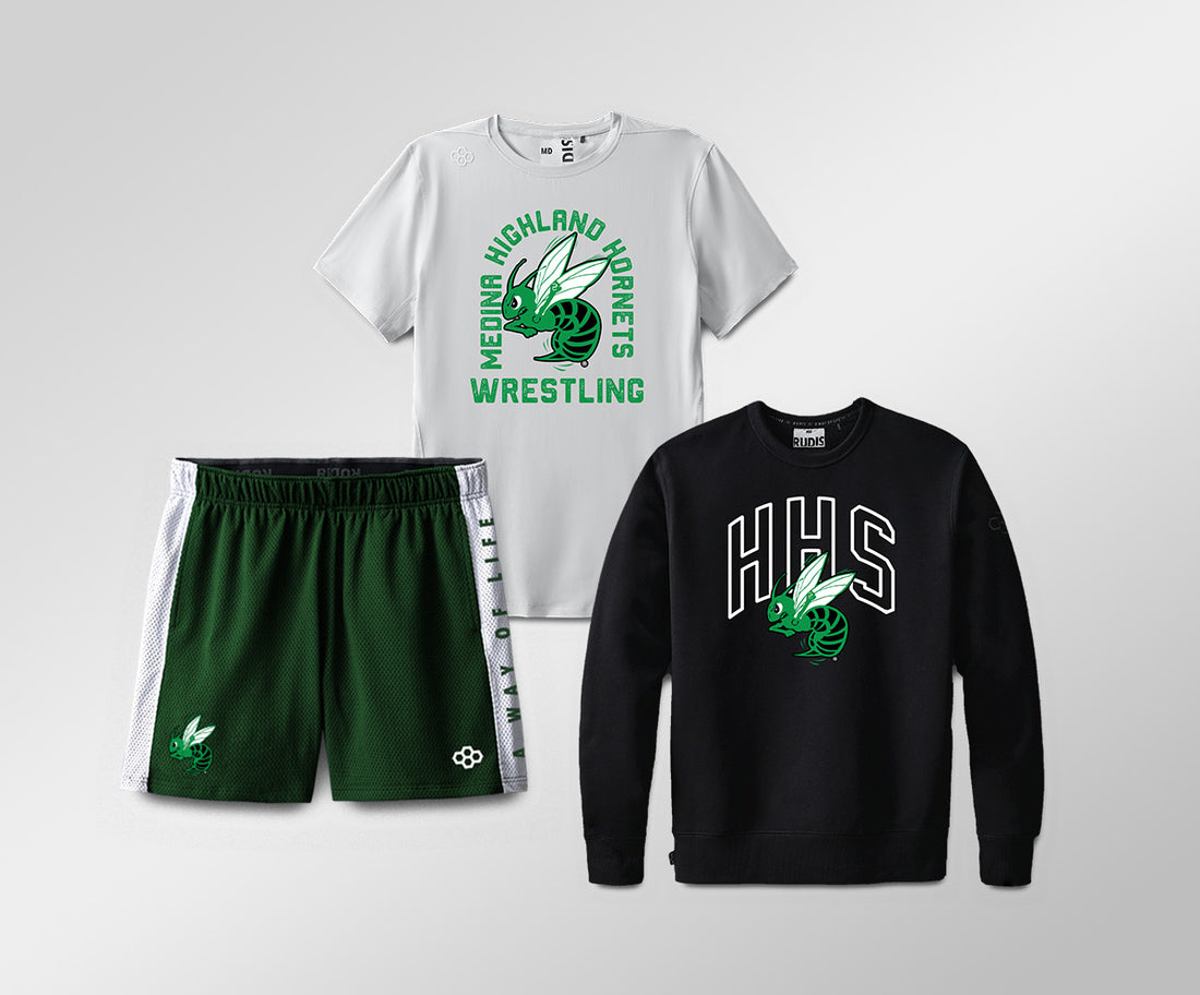 Custom school training apparel showing White t-shirt, green shorts, and black sweatshirt with logos on a light gray background