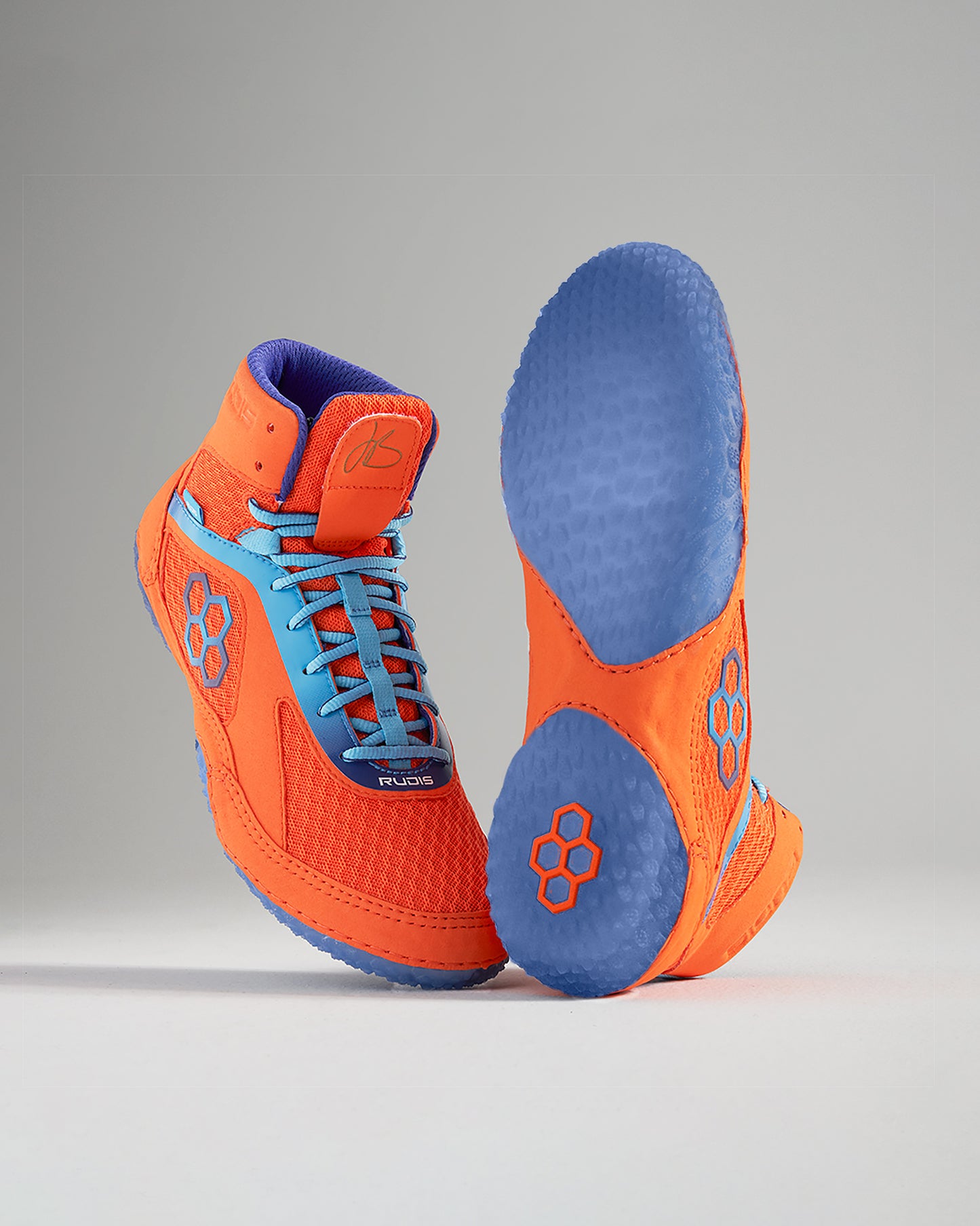 Vibrant orange wrestling shoes with blue accents and a textured sole for optimal grip and performance