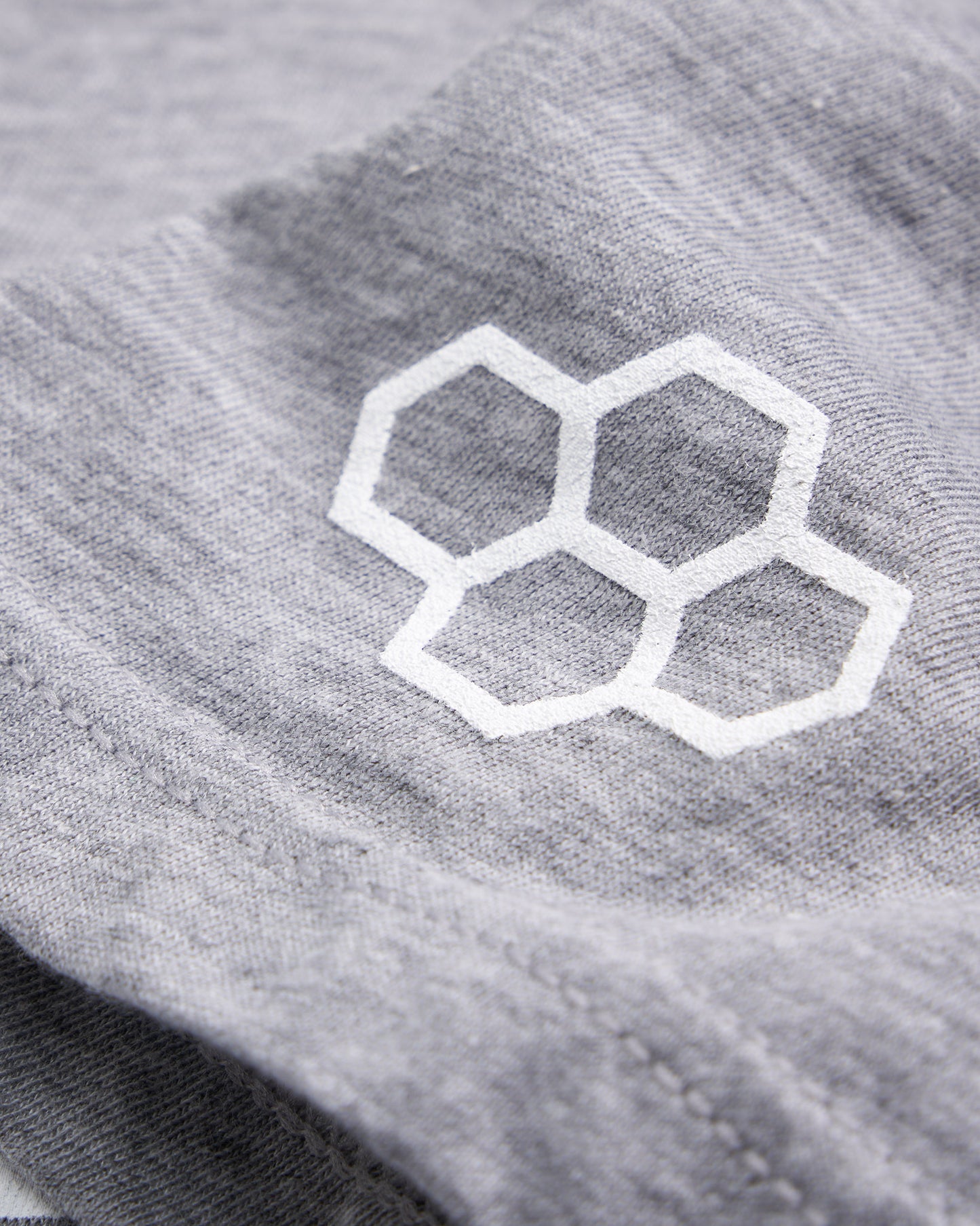A close-up view of a light gray fabric featuring a white hexagonal logo highlighting the texture and detail of the material