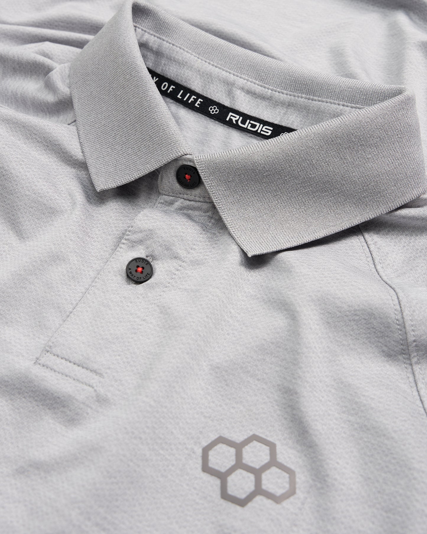 A detailed view of a light gray polo shirt featuring a stylish collar black buttons and a subtle honeycomb logo design