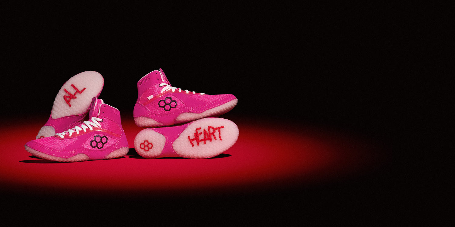 RUDIS Alpha 2.0 wrestling shoes in All Heart pink colorway with bold outsole graphics showcasing grip, lightweight design, and aggressive mat traction