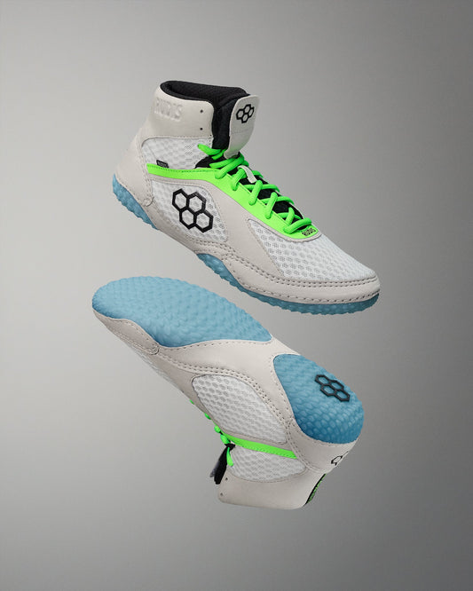 White wrestling shoes with green laces and blue soles on a gray background