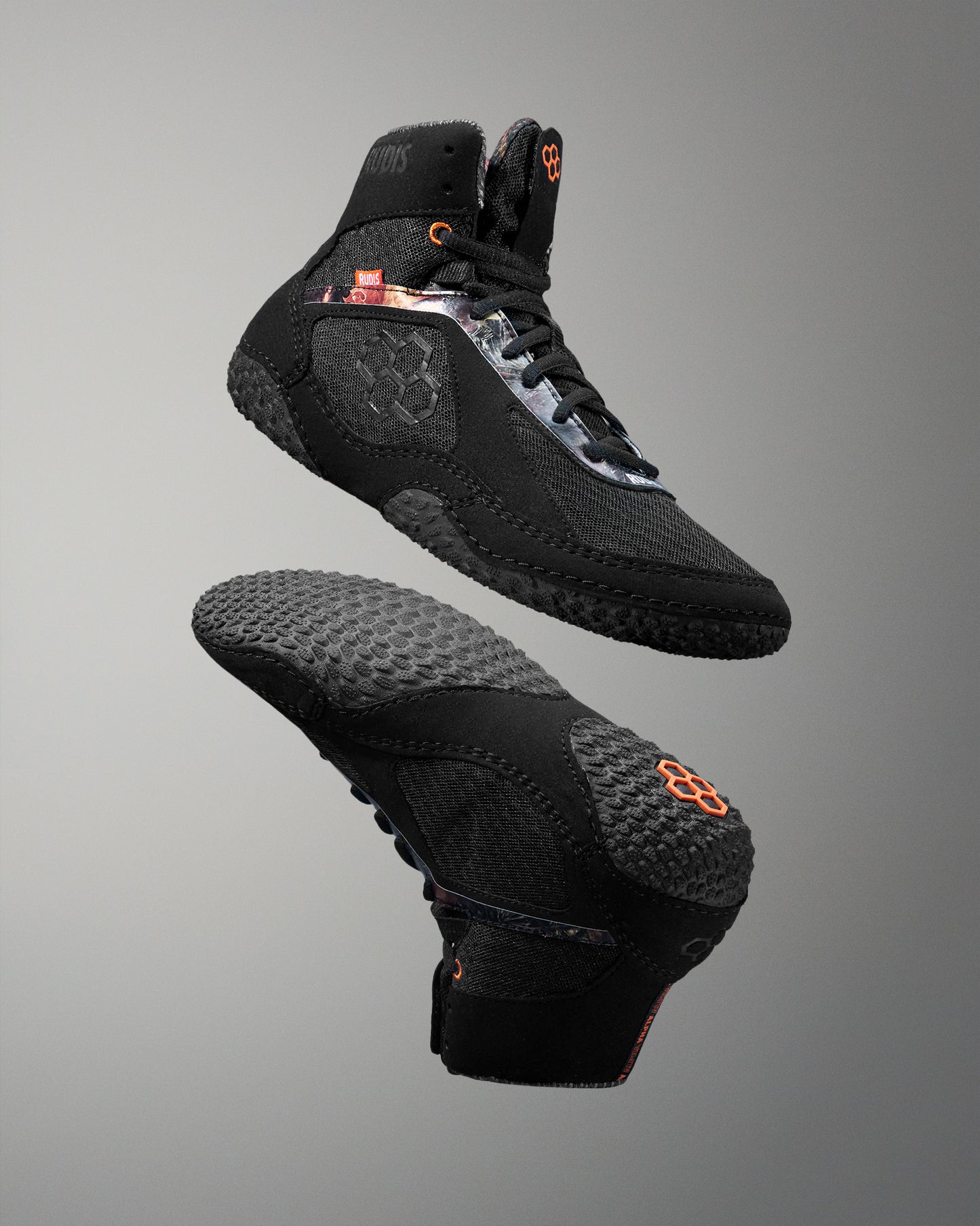Black wrestling shoe with orange accents on a gray background