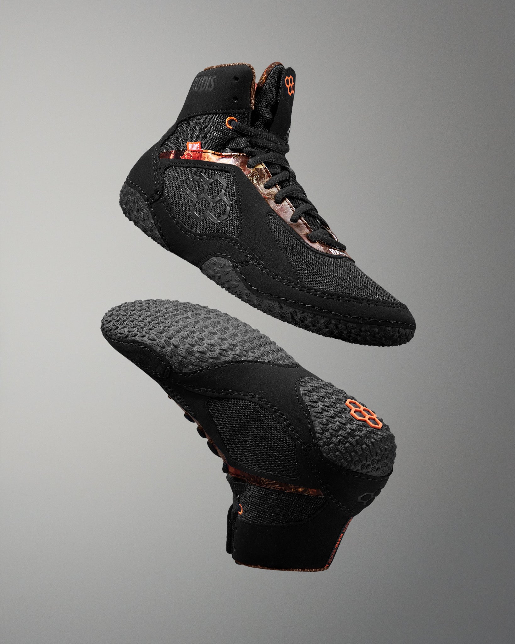 Black high-top sneakers with orange accents on a gray background