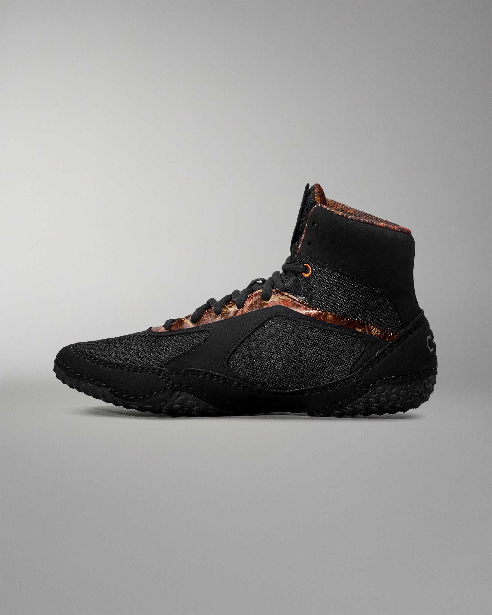 Black high-top sneaker with brown accents on a gray background