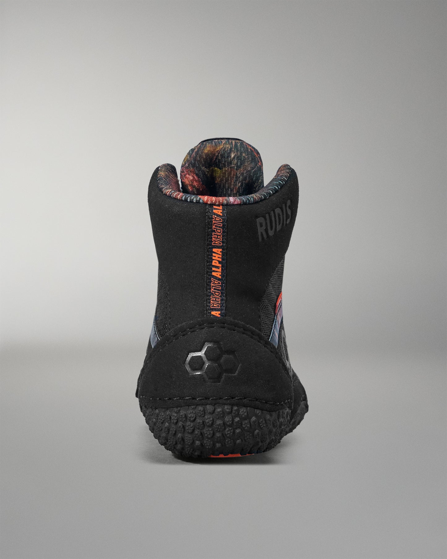 Black wrestling shoe with orange text on a gray background
