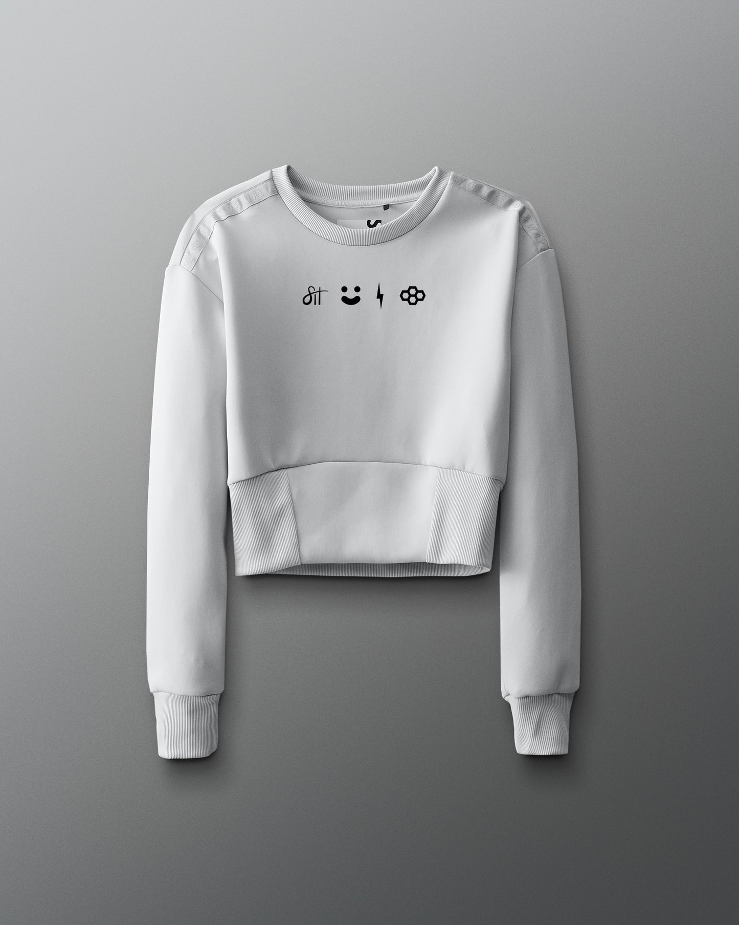 White cropped sweatshirt with black graphics on a gray background