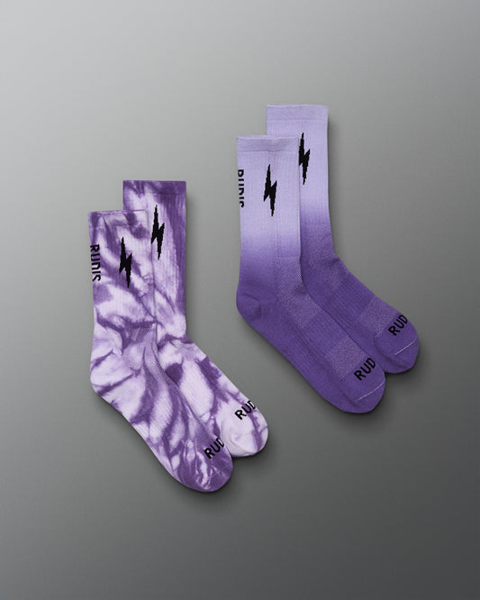 Two purple socks with a tie-dye pattern and lightning bolt design on a gray background