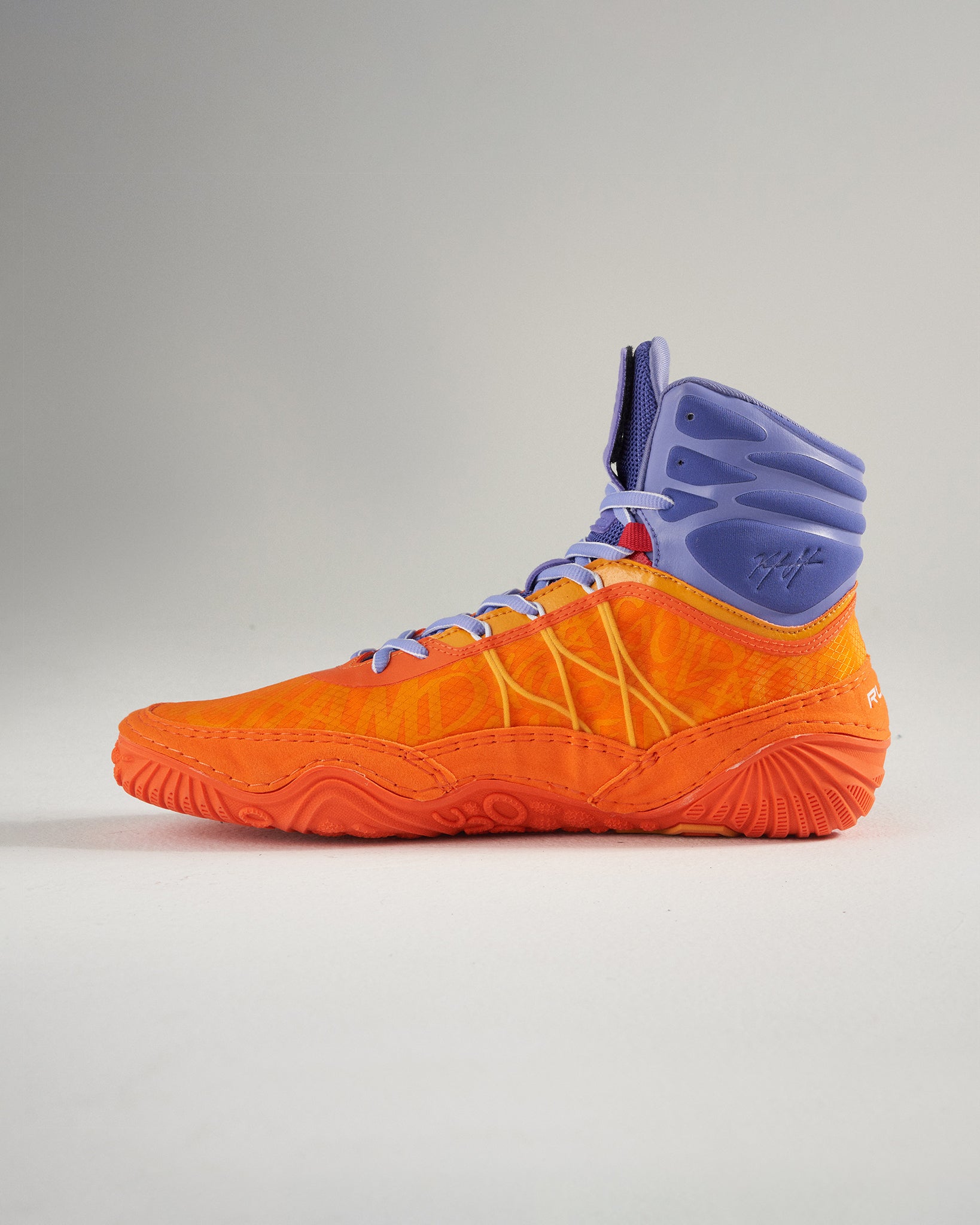 A vibrant orange basketball shoe with purple accents featuring a high-top design and textured sole for enhanced grip and performance