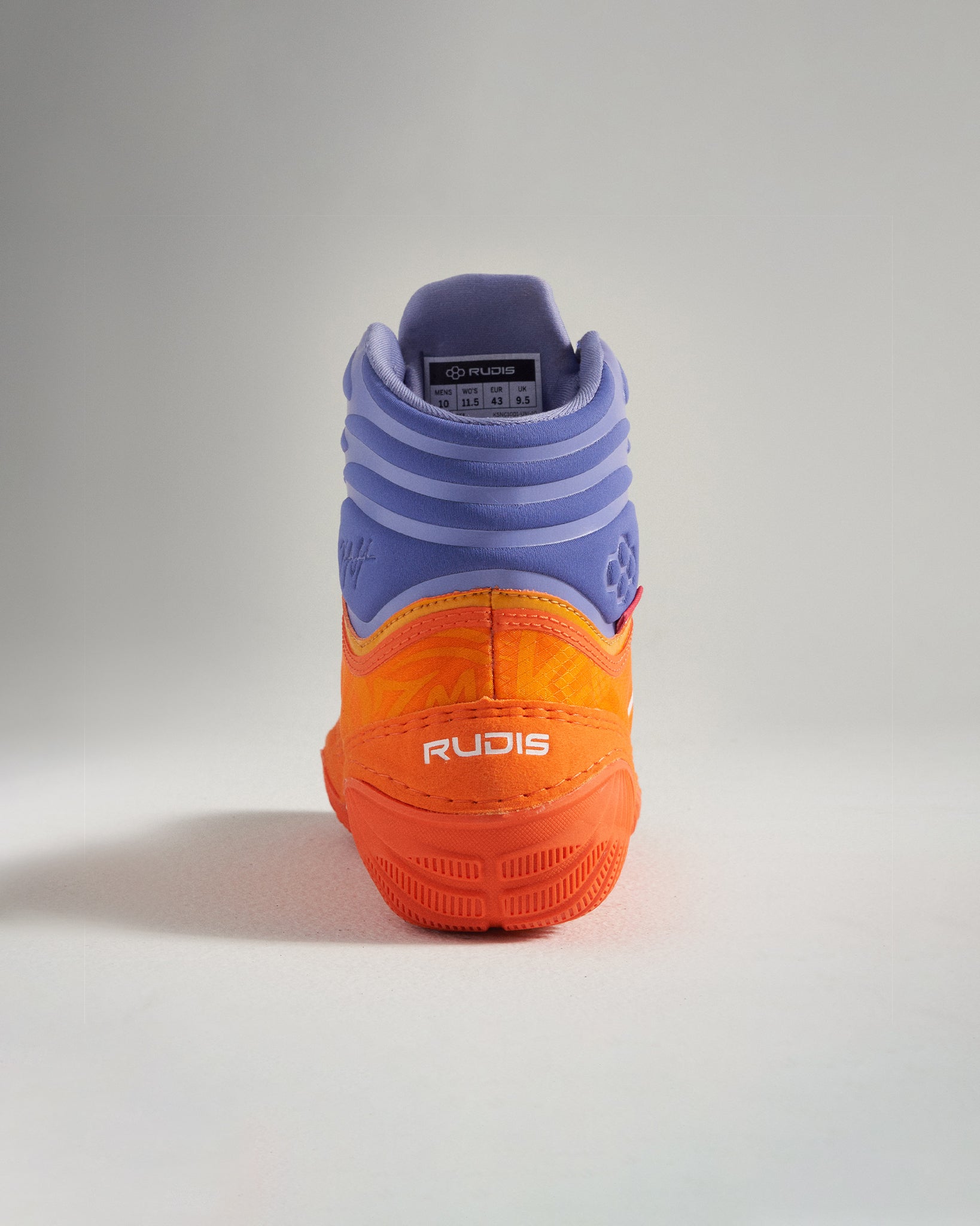 A vibrant pair of wrestling shoes featuring a striking combination of purple and orange colors with the brand name RUDIS prominently displayed on the heel
