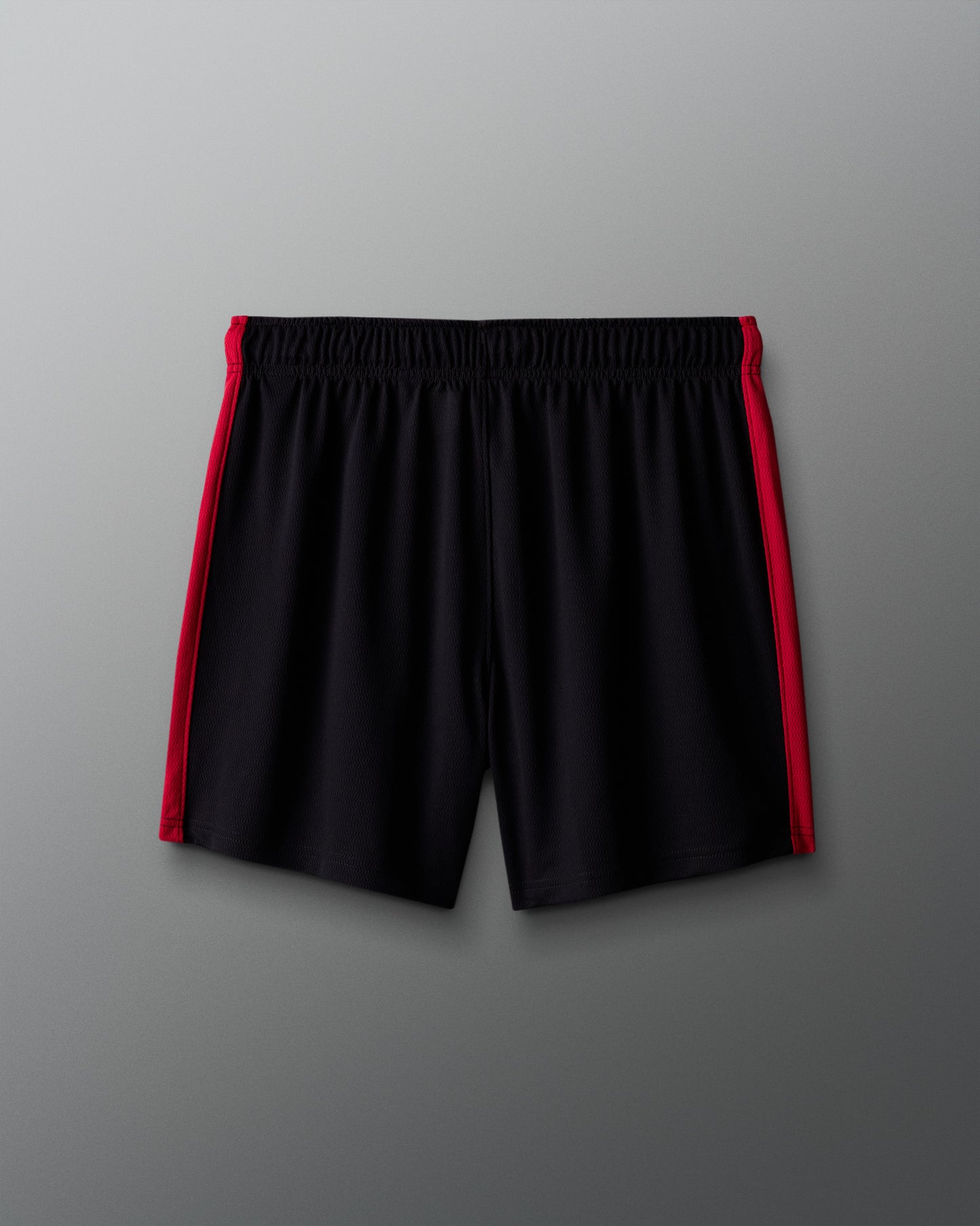 Black shorts with red side panels on a gray background