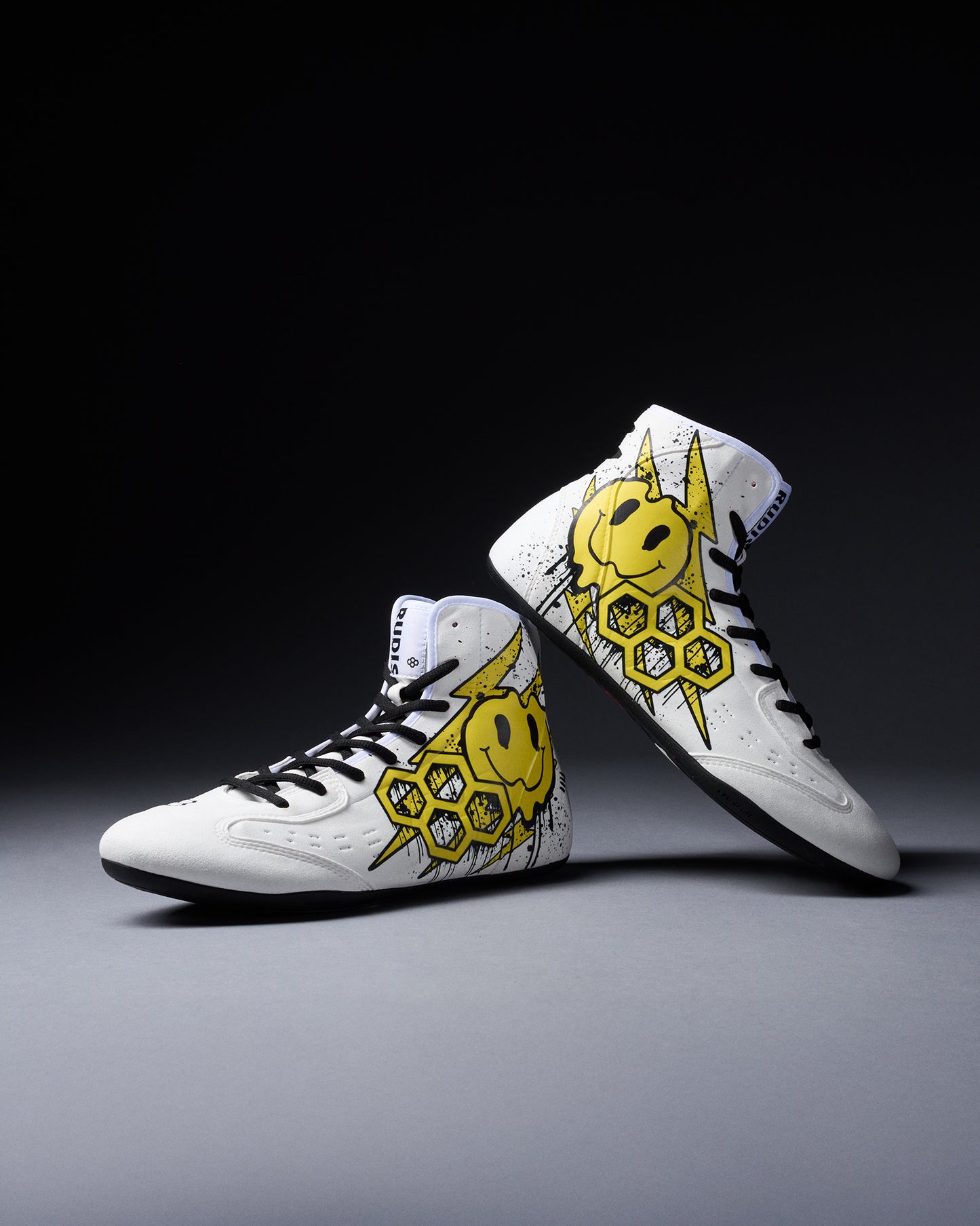 White wrestling shoes with yellow smiley face design on a dark background