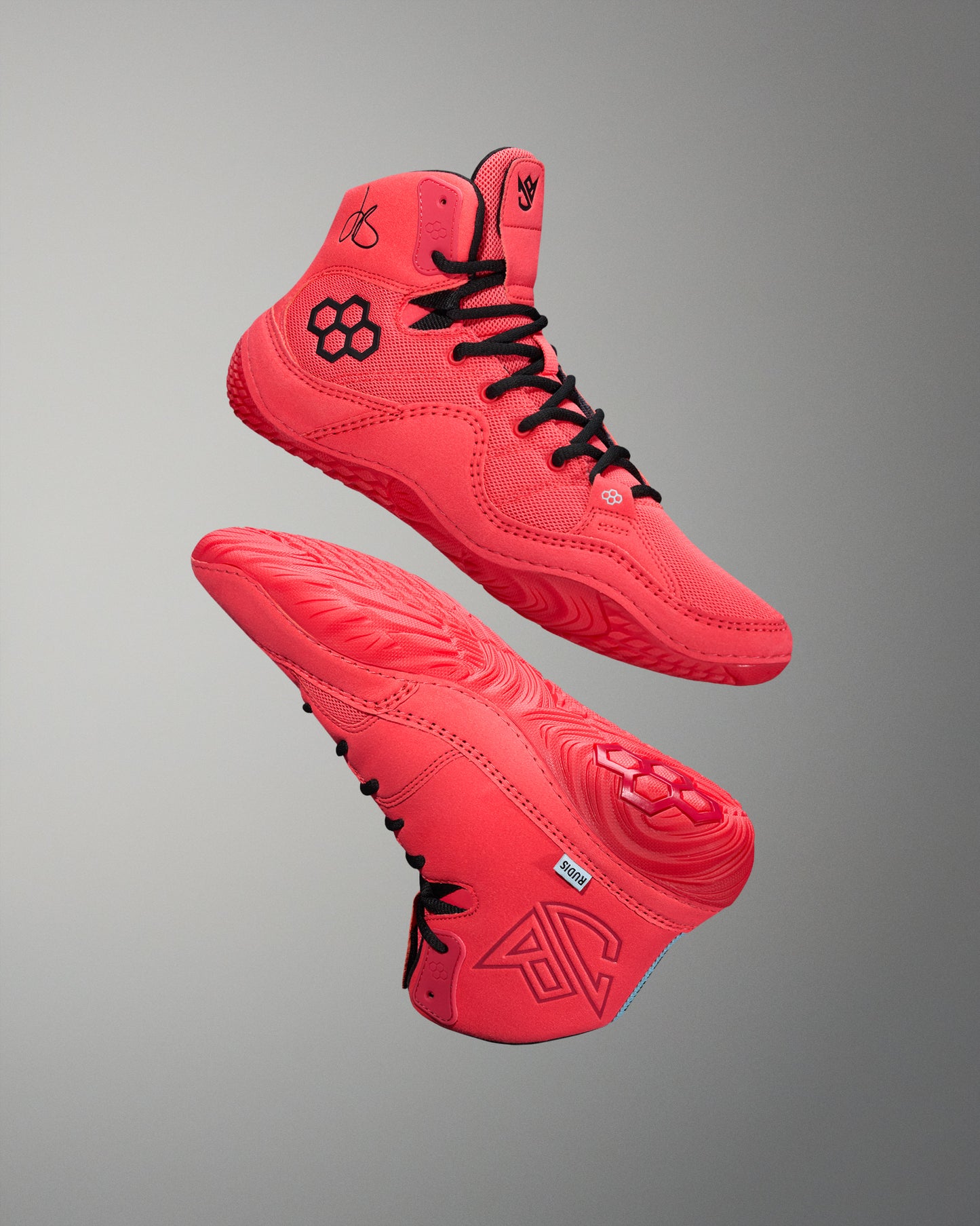 Red wrestling shoes with black RUDIS quad hex logo.