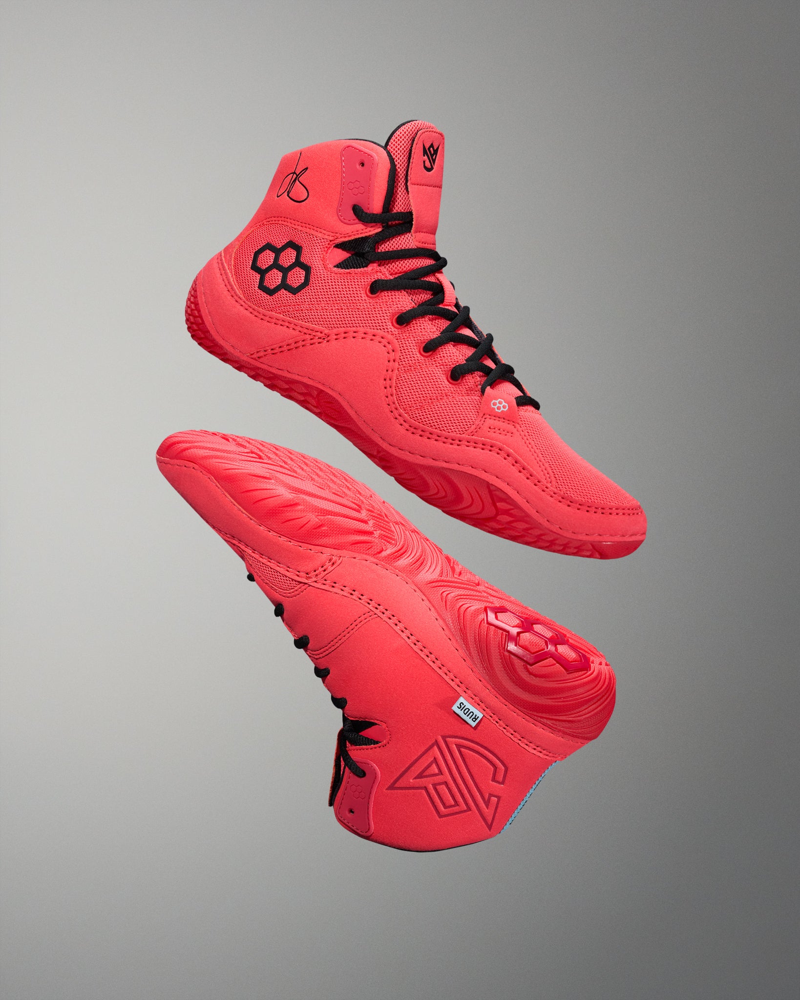Red wrestling shoes with black RUDIS quad hex logo.