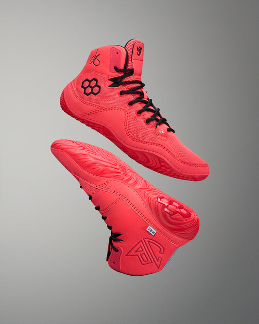 Red wrestling shoes with black RUDIS quad hex logo.