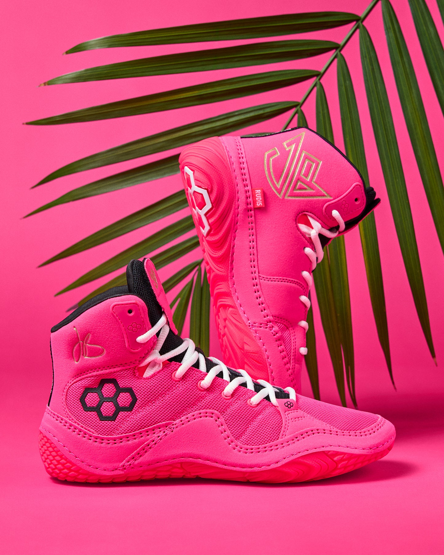 Pink high-top Wrestling Shoes with black and white accents on a pink background with palm leaves.