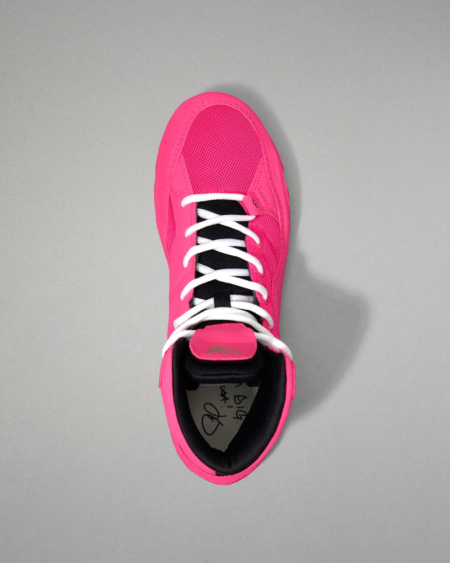 Pink wrestling shoe with white laces on a gray background
