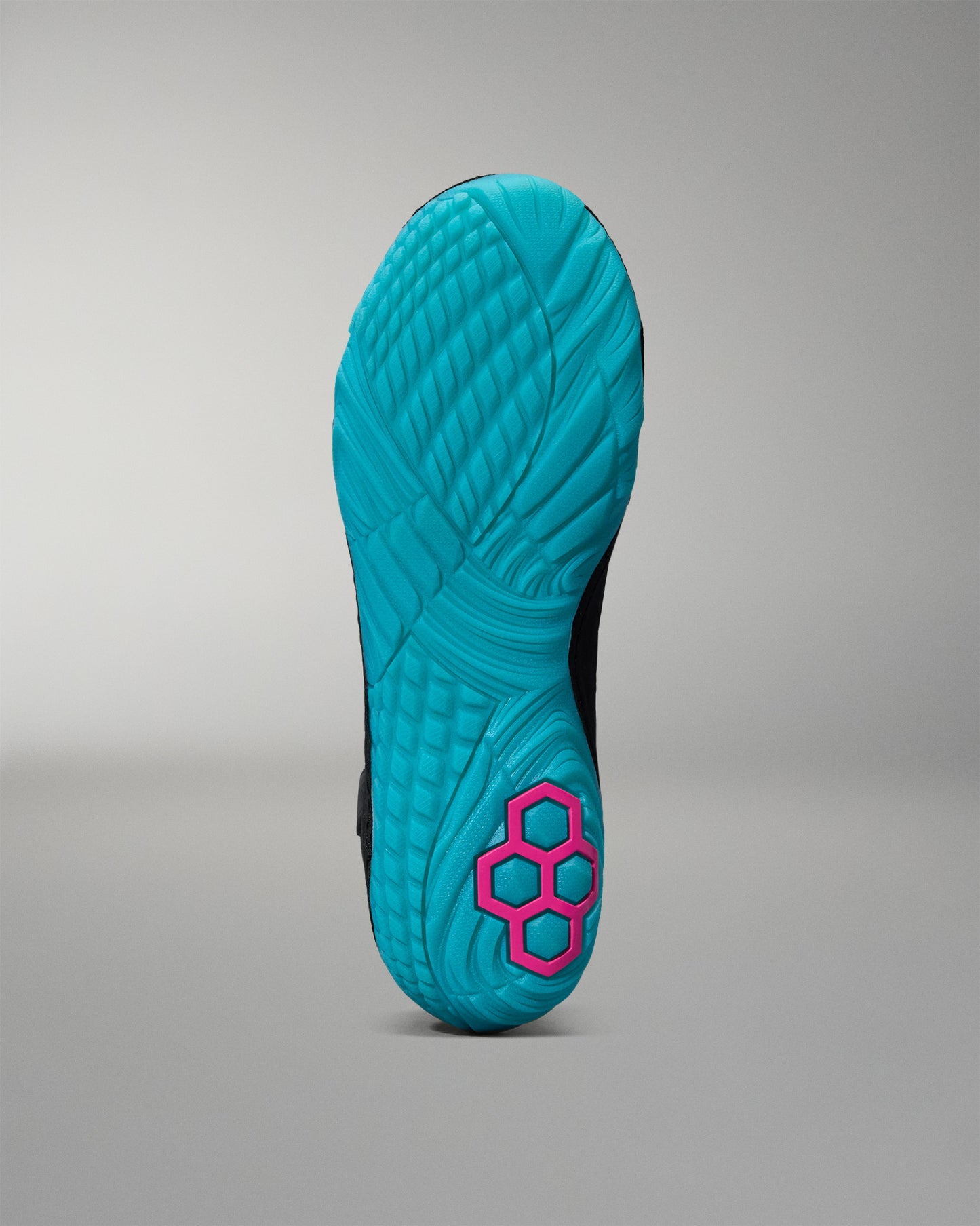 Turquoise sole of a Wrestling shoe with pink hexagonal pattern on a gray background