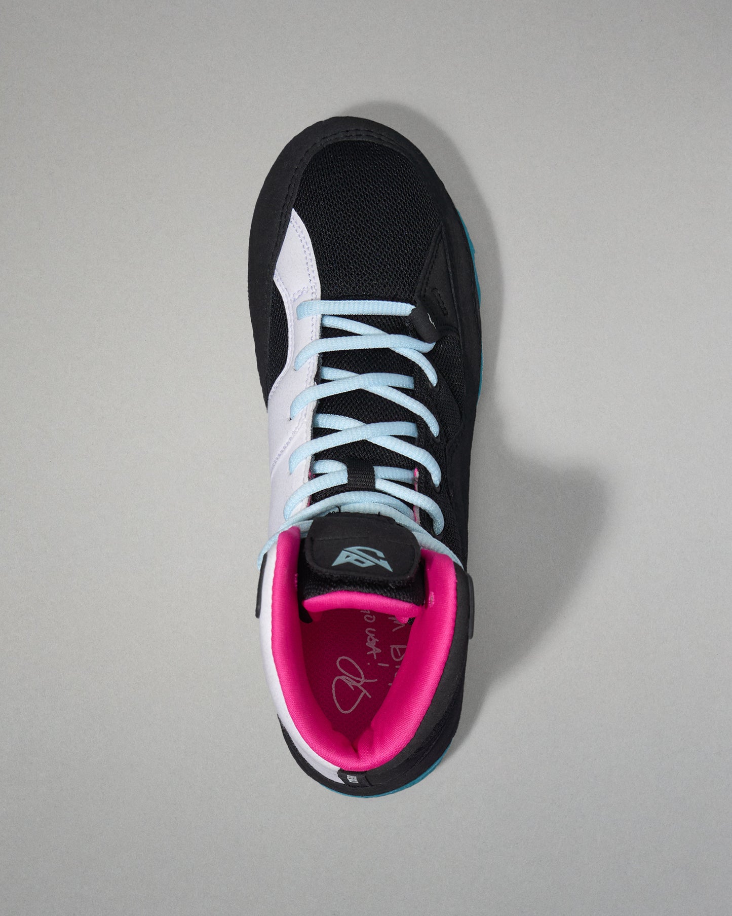 Black and pink wrestling shoe with white laces on a gray background