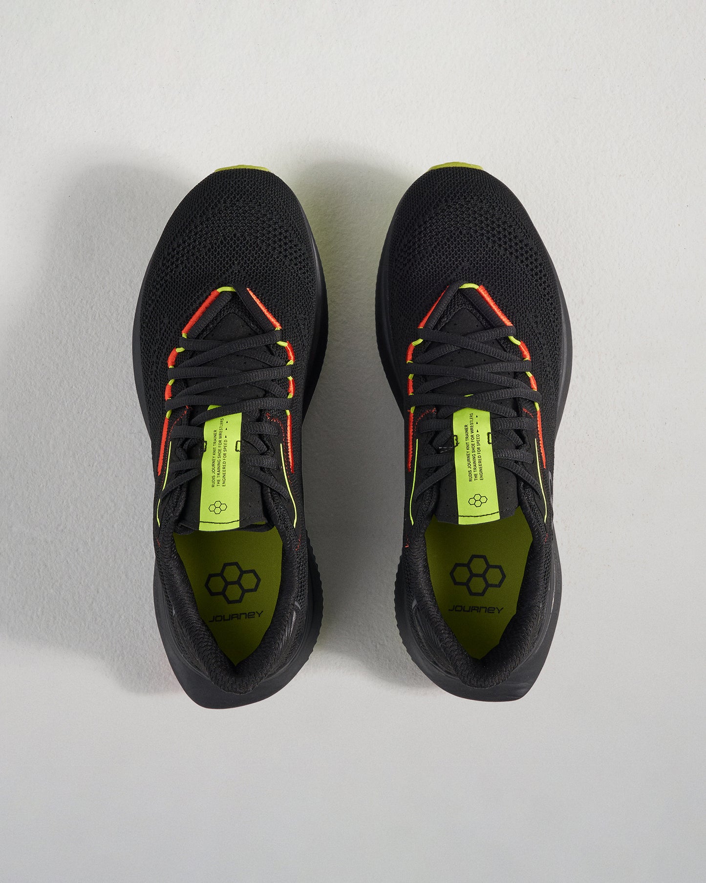 A pair of black athletic shoes with vibrant yellow and red accents showcasing a breathable mesh upper and a modern design