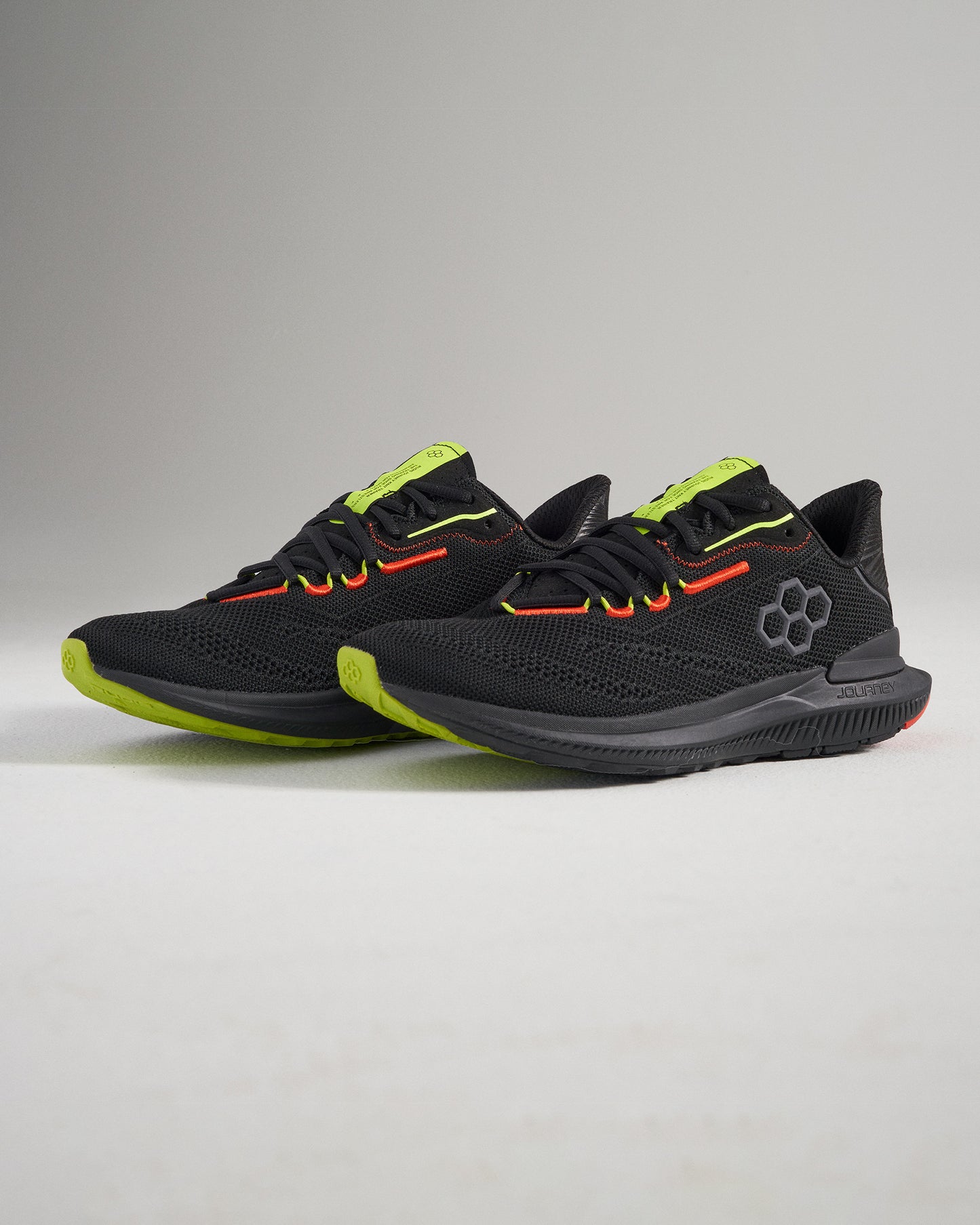This image displays a stylish pair of black athletic shoes with bright green and red accents designed for performance and comfort