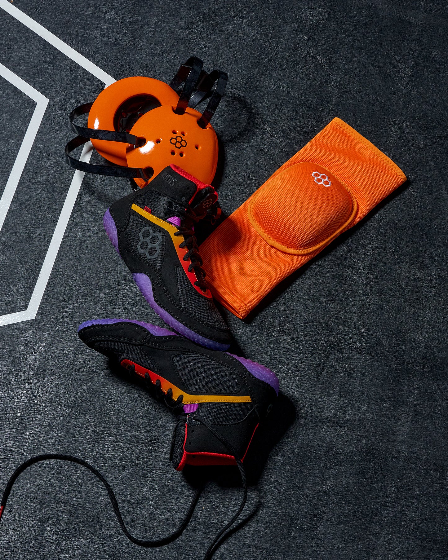 Black and orange wrestling shoe with a knee pad on a textured surface