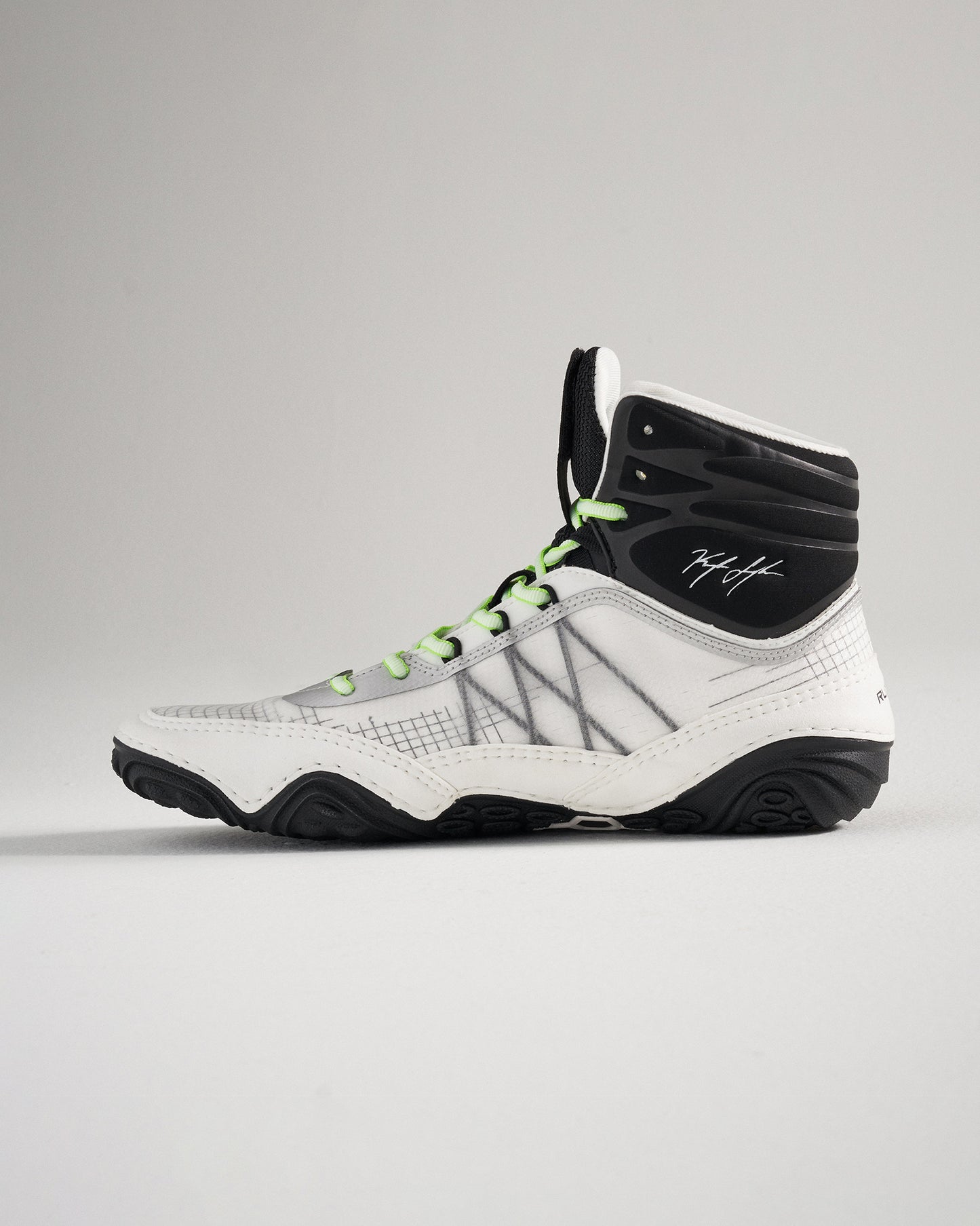 A modern white and black high-top athletic shoe with green accents featuring a unique design and textured sole for enhanced performance