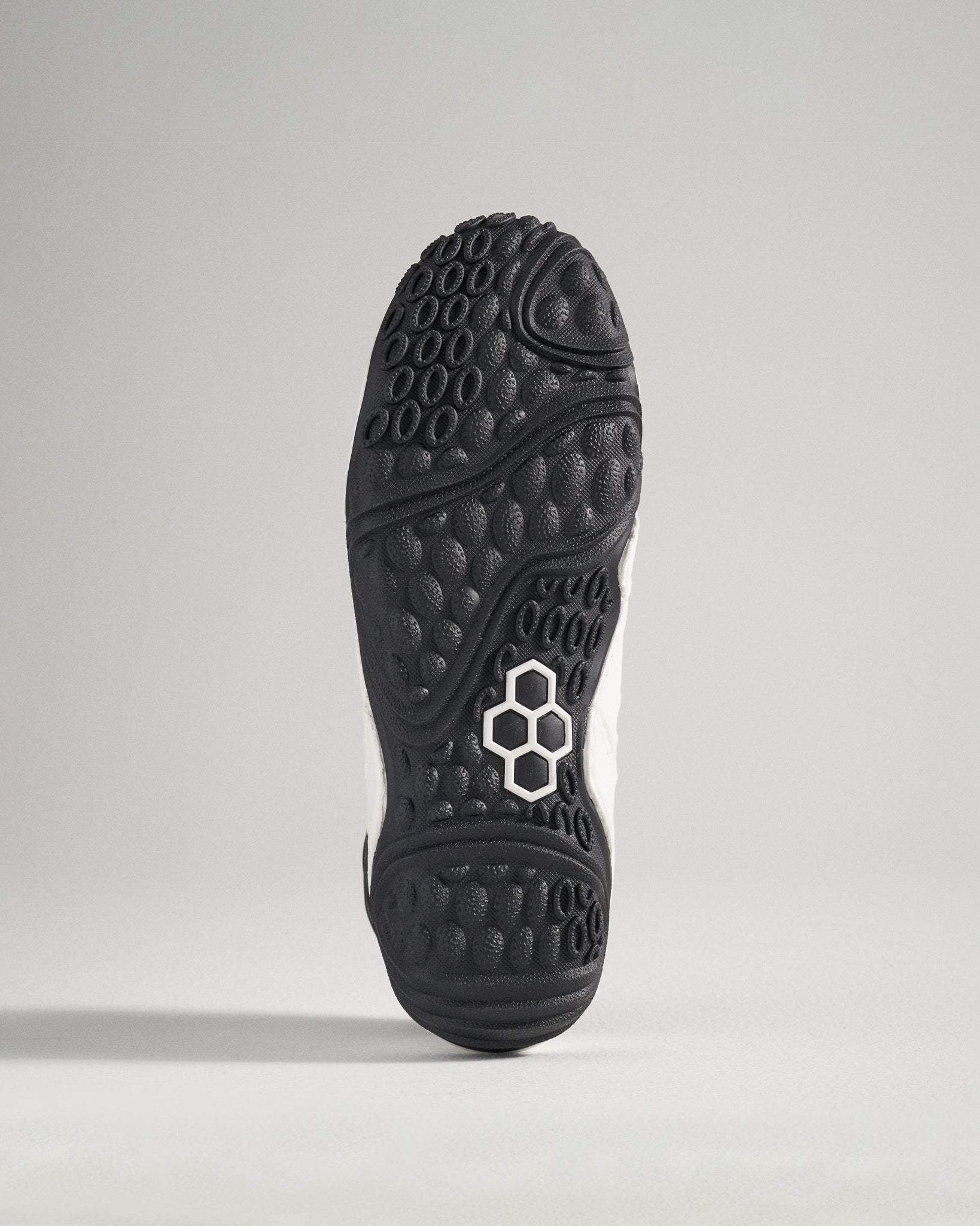 The image displays the sole of a modern athletic shoe showcasing its intricate tread patterns and textured grip for enhanced performance