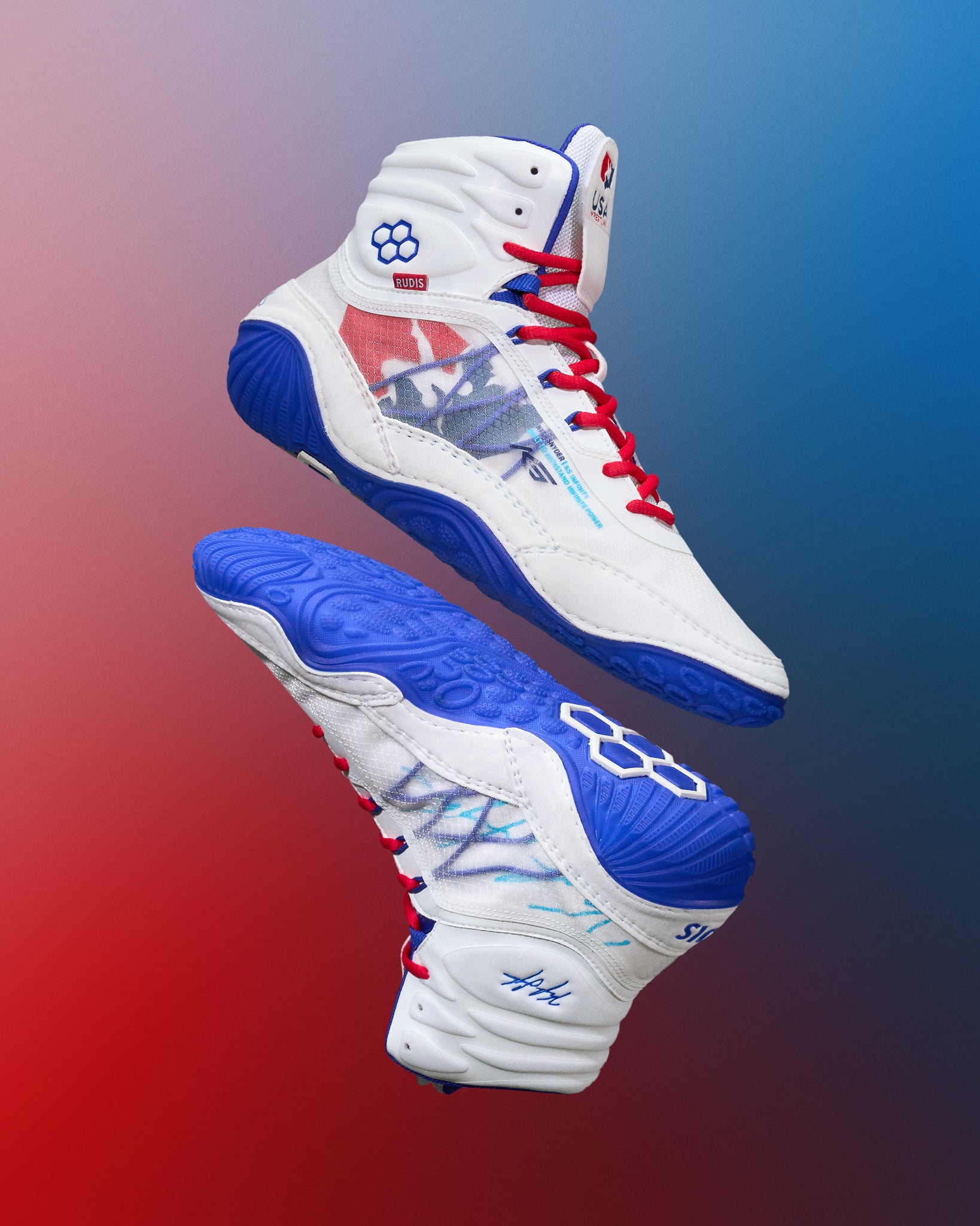 Side and bottom view of a pair of white, blue, and red RUDIS KS Infinity Edge Wrestling Shoes featuring the USA Wrestling logo, hexagon RUDIS branding, red laces, blue soles, and Kyle Snyder’s signature on the heel.