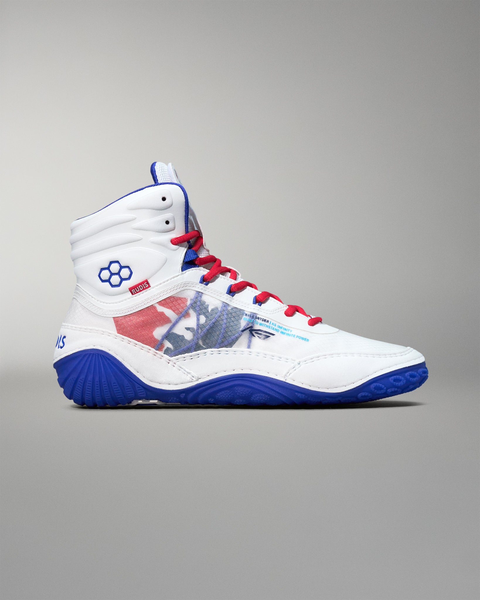 Side view of a white RUDIS KS Infinity Edge Wrestling Shoe featuring a red, white, and blue USA flag-inspired design, red laces, blue outsole, RUDIS hexagon logo near the ankle, and official USA Wrestling branding
