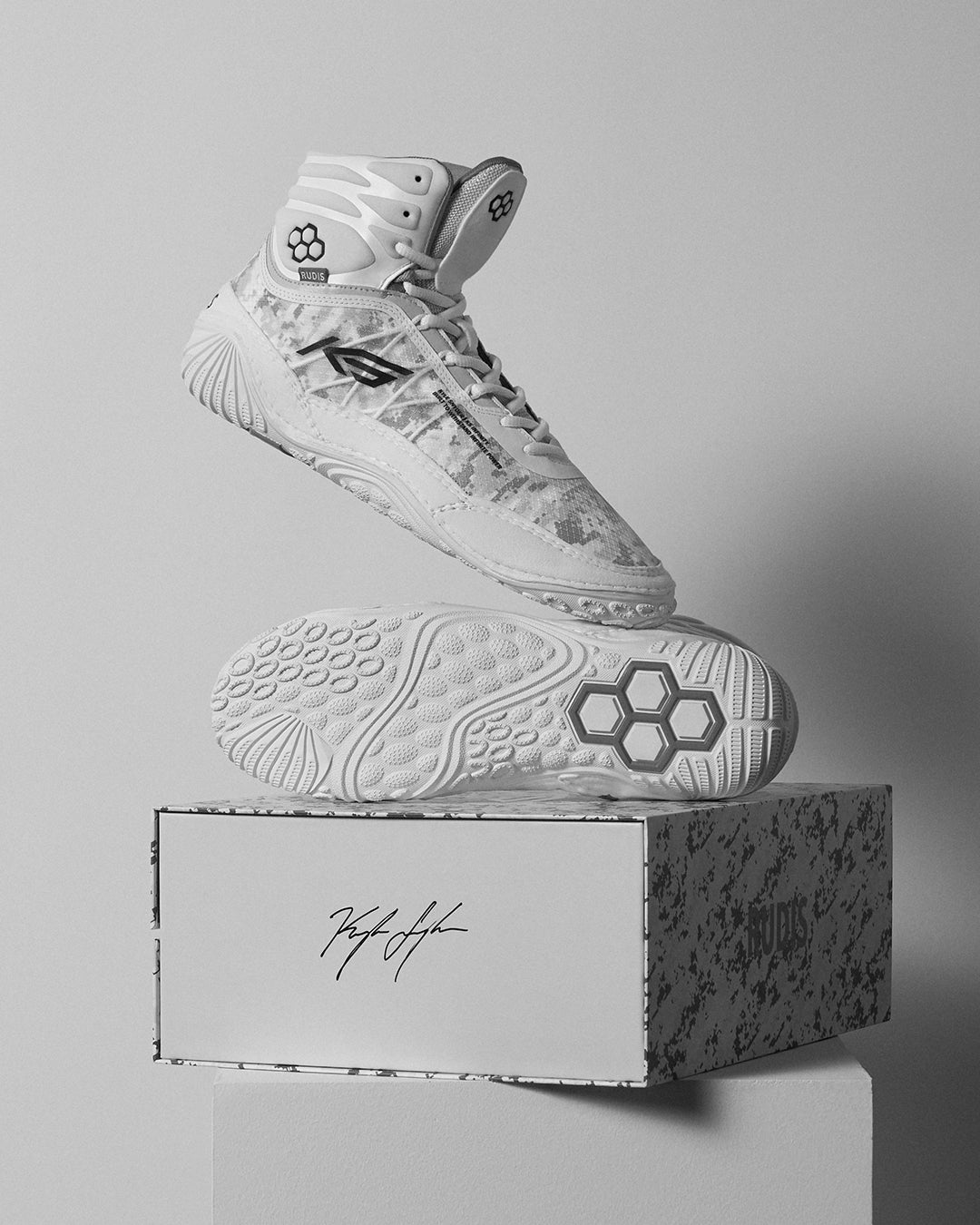 A pair of white KS Infinity Edge Adult Wrestling Shoes placed on a box with a patterned design and the signature of an individual on the box.