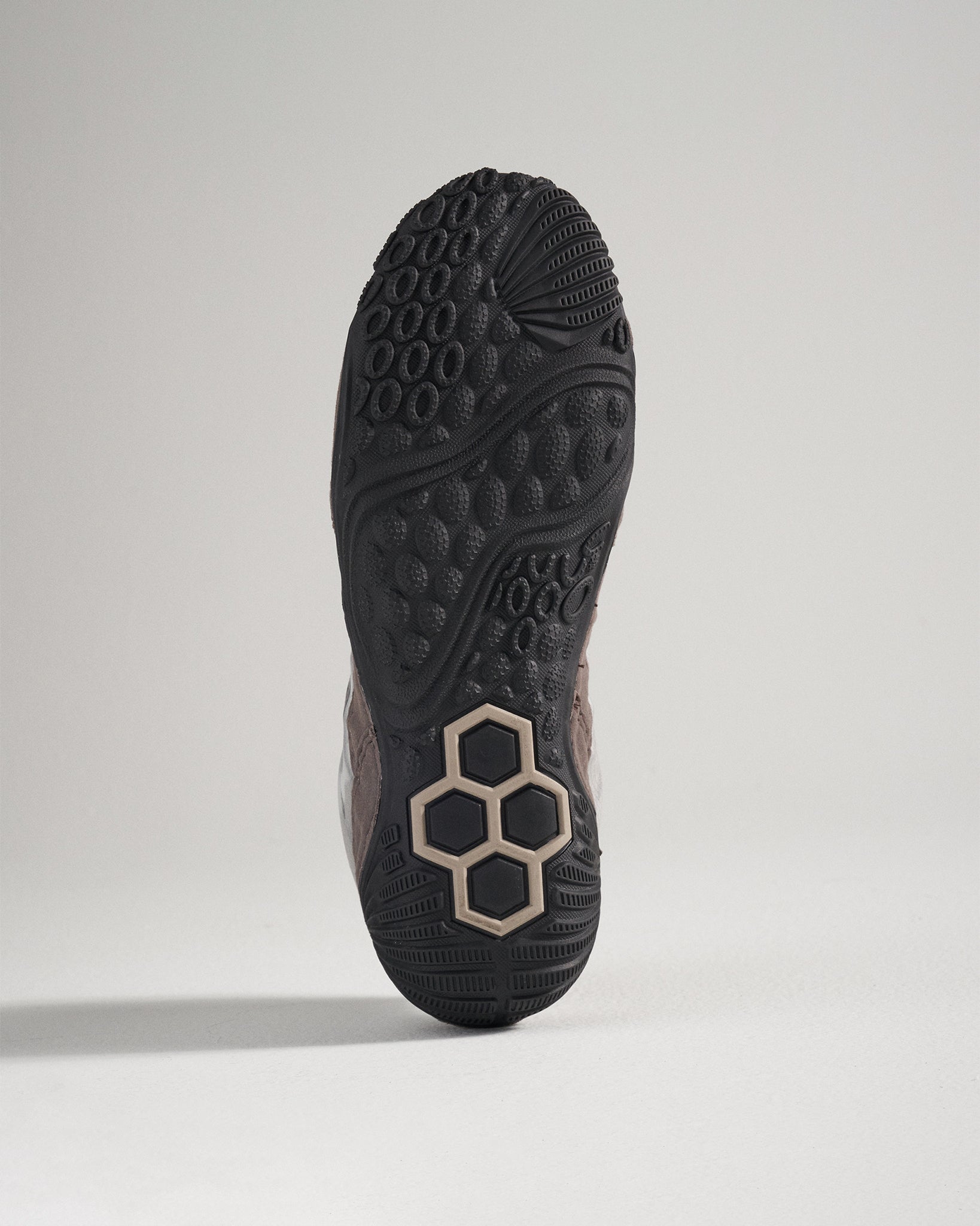 This image displays the detailed underside of a modern athletic shoe featuring a textured black rubber sole with unique patterns for enhanced grip and traction