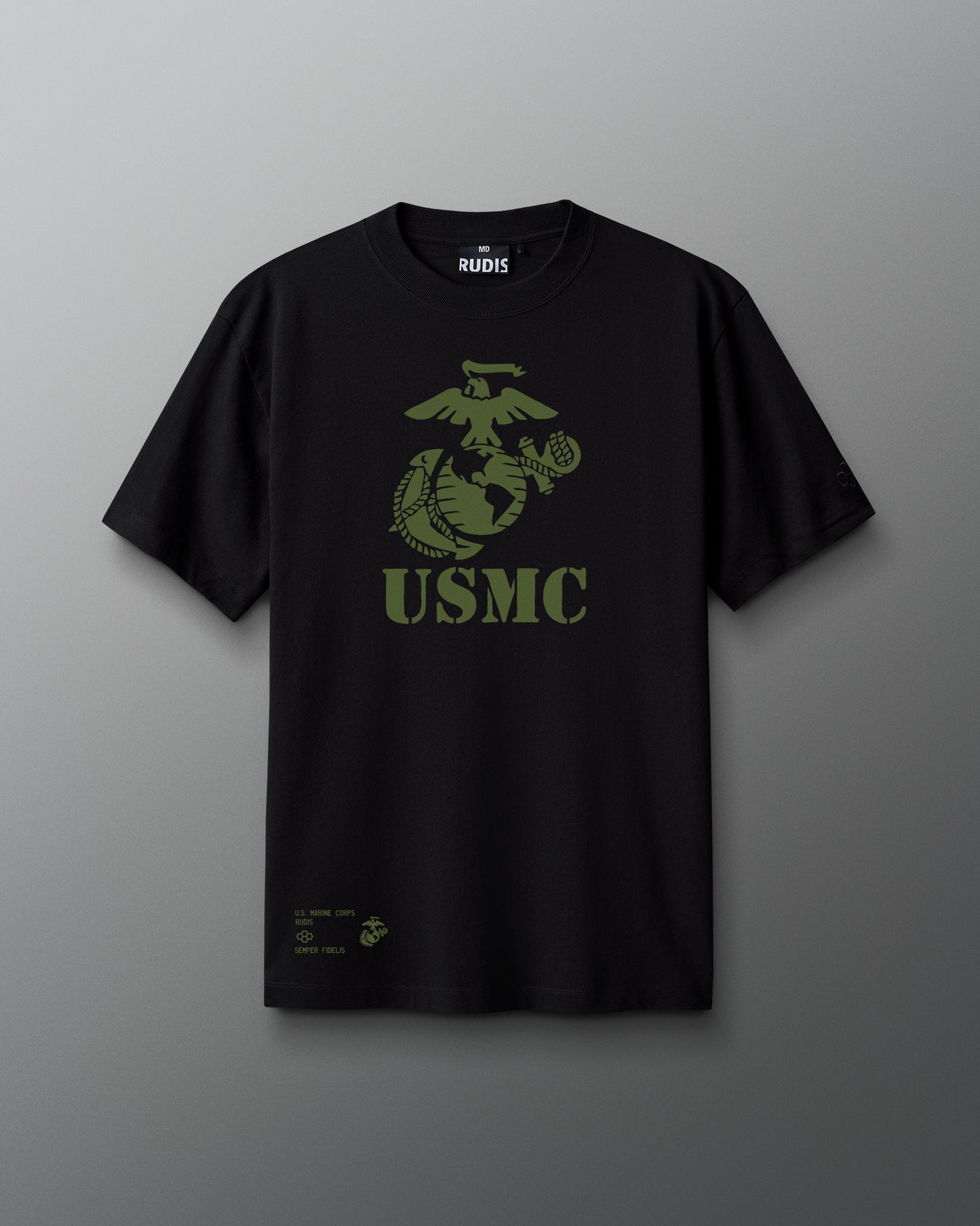 Front view of a black RUDIS T-shirt featuring a large olive green USMC eagle, globe, and anchor emblem with ‘USMC’ in stencil-style lettering. Small print at the hem reads ‘U.S. Marine Corps,’ ‘RUDIS,’ and ‘Semper Fidelis.