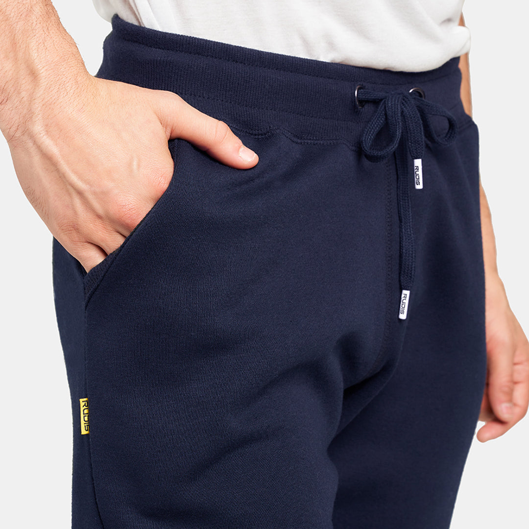 A close-up view of a man wearing navy blue sweatpants with a hand resting in the side pocket showcasing a casual and comfortable style