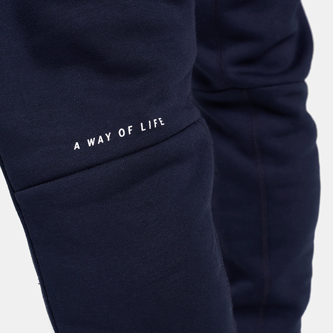 Close-up view of navy sweatpants featuring the phrase A WAY OF LIFE in white embroidery on the thigh