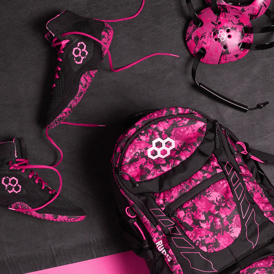 RUDIS Pink Power Collection featuring bold pink and black wrestling gear including backpacks, wrestling shoes, apparel, headgear, knee pads, and shorts – designed for wrestlers who want style and performance on and off the mat.