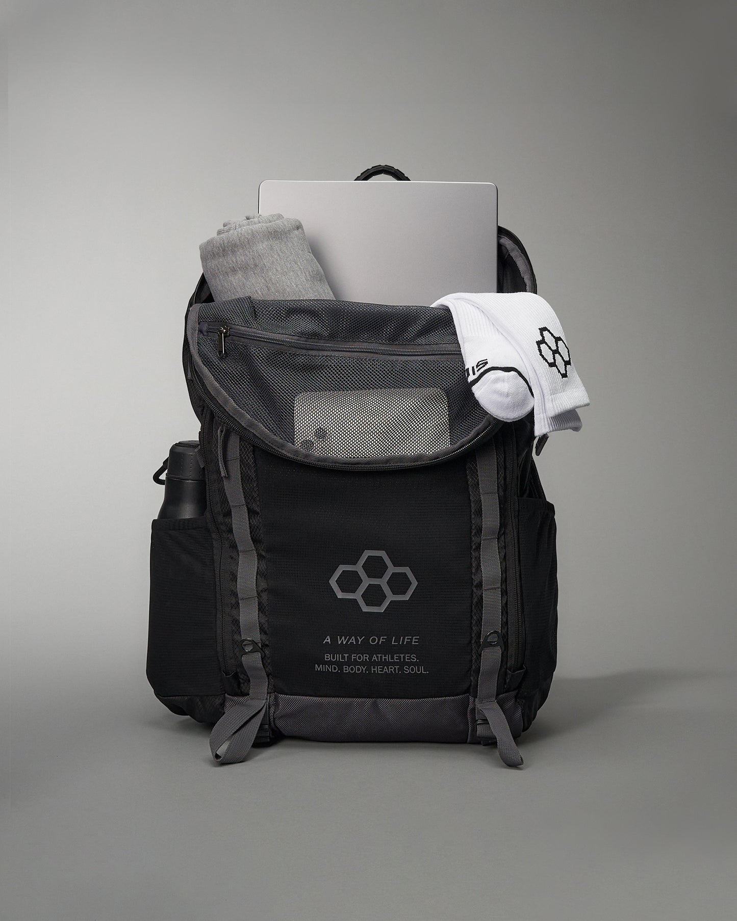 A stylish black athletic backpack filled with essential items for an active lifestyle including a laptop workout clothes and socks