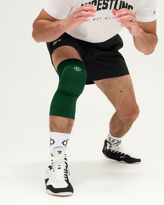 Person wearing a green knee pad on a white background
