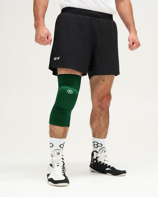 Person wearing a green knee pad on a white background