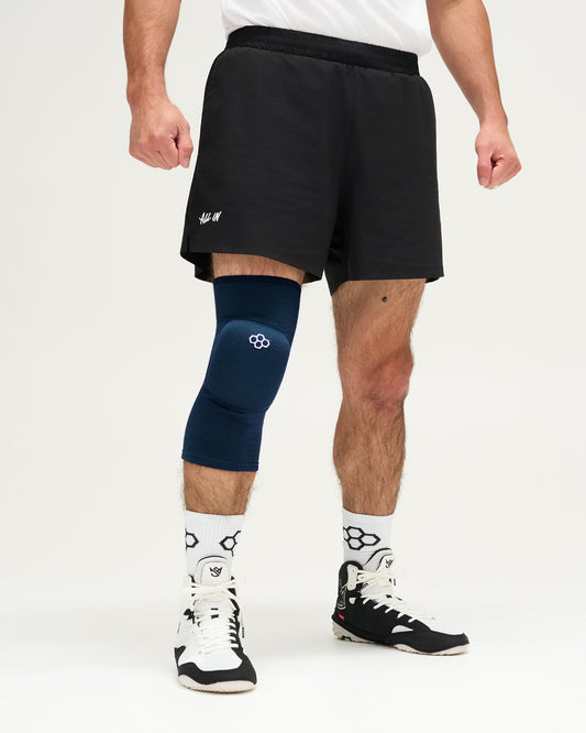 Person wearing blue knee pads and white sneakers on a plain background