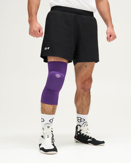 Person wearing a purple knee brace on a white background