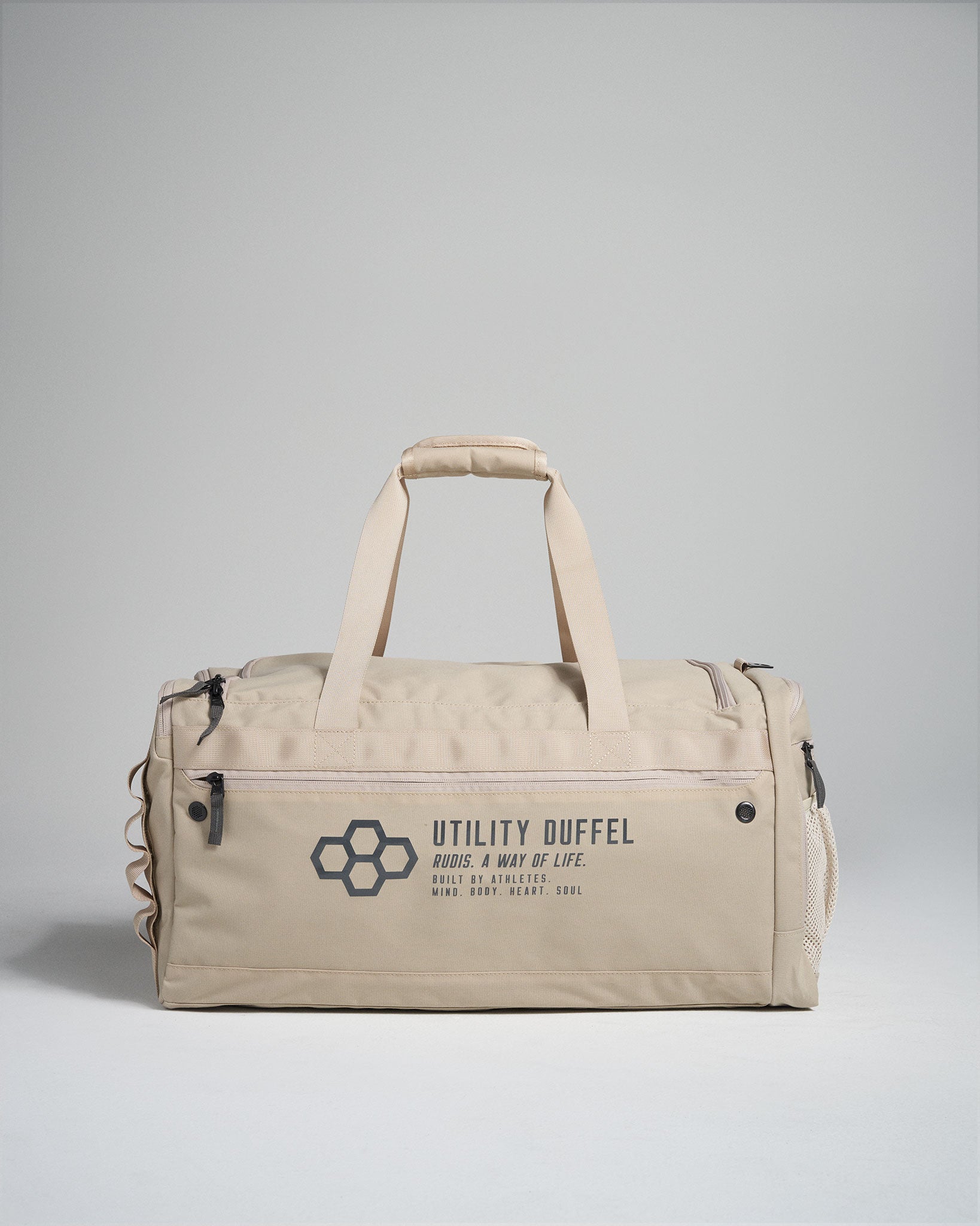 A beige utility duffel bag featuring multiple zippered compartments and a modern design highlighted by an embossed logo and tagline emphasizing its athletic purpose
