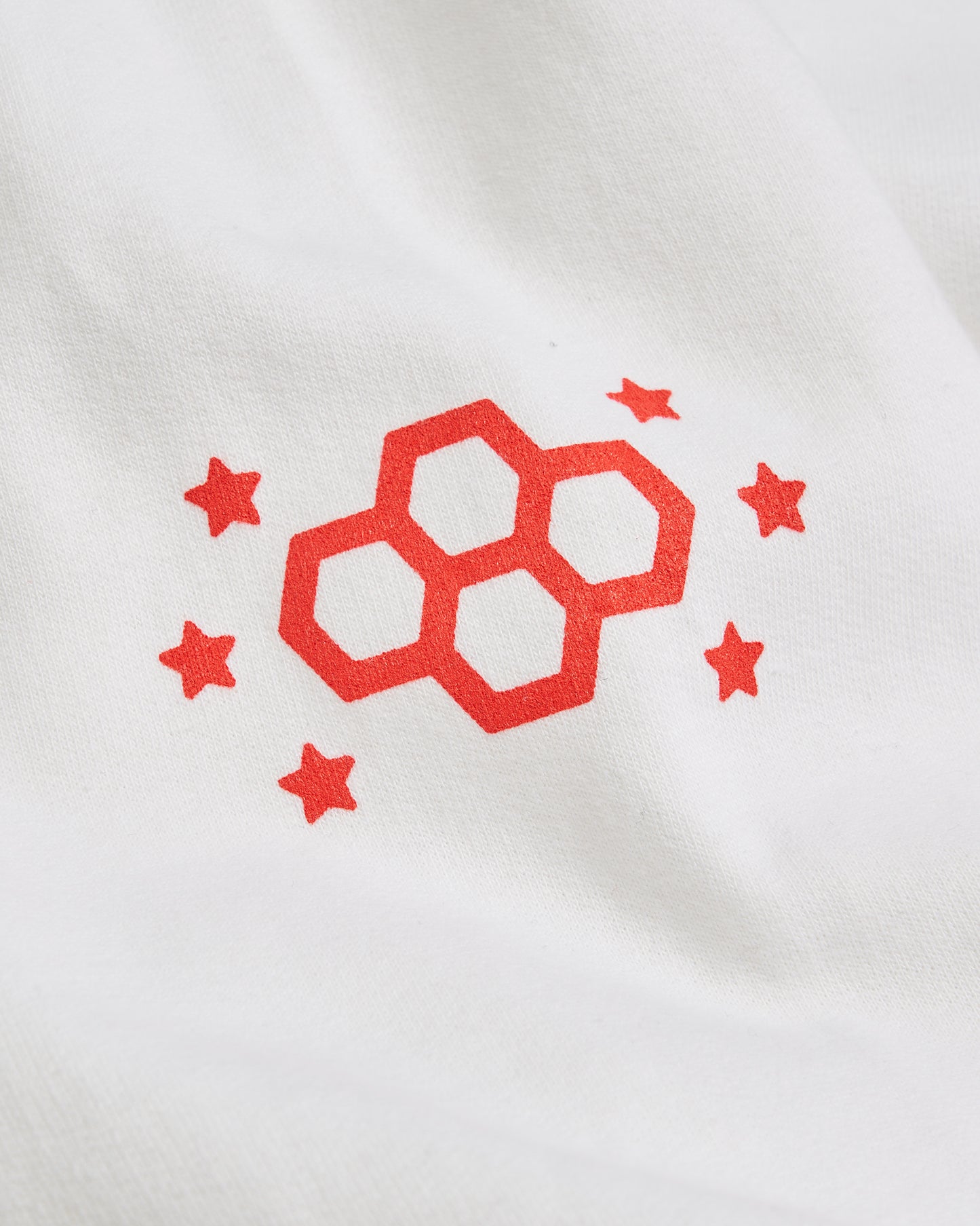 A minimalist design featuring a red graphic of interlocking hexagons and stars on a white fabric background