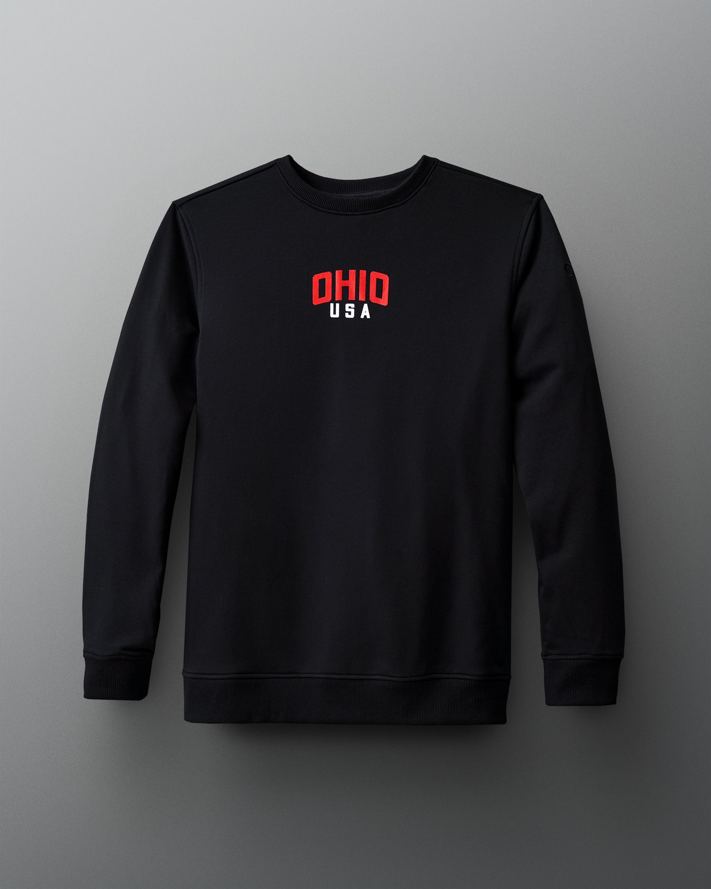 Front view of the RUDIS Team Ohio Arched Crewneck in black, featuring a small red and white 'OHIO USA' graphic centered on the chest, with a clean, minimalist design.