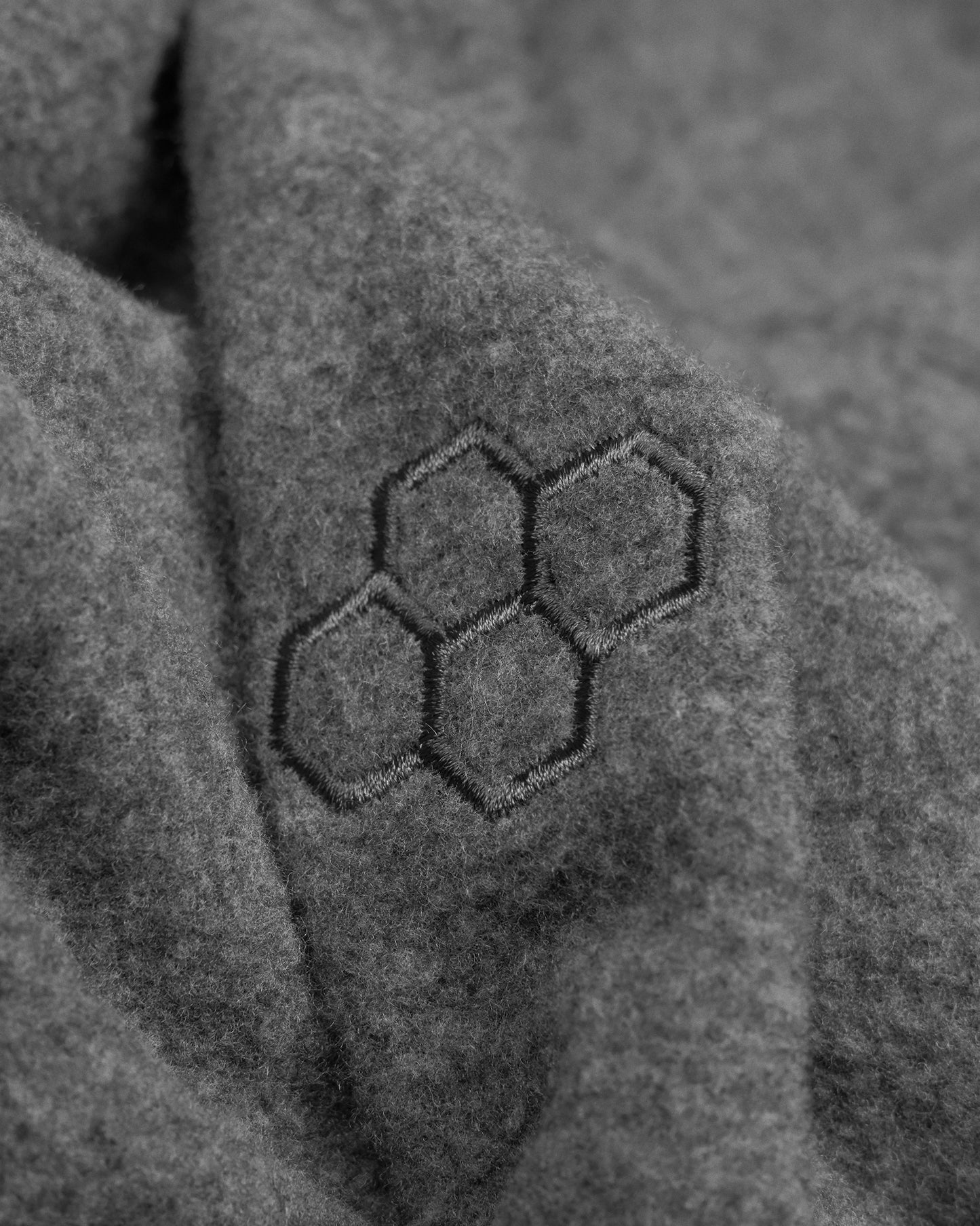 Close-up of textured fabric with a hexagonal pattern RUDIS logo