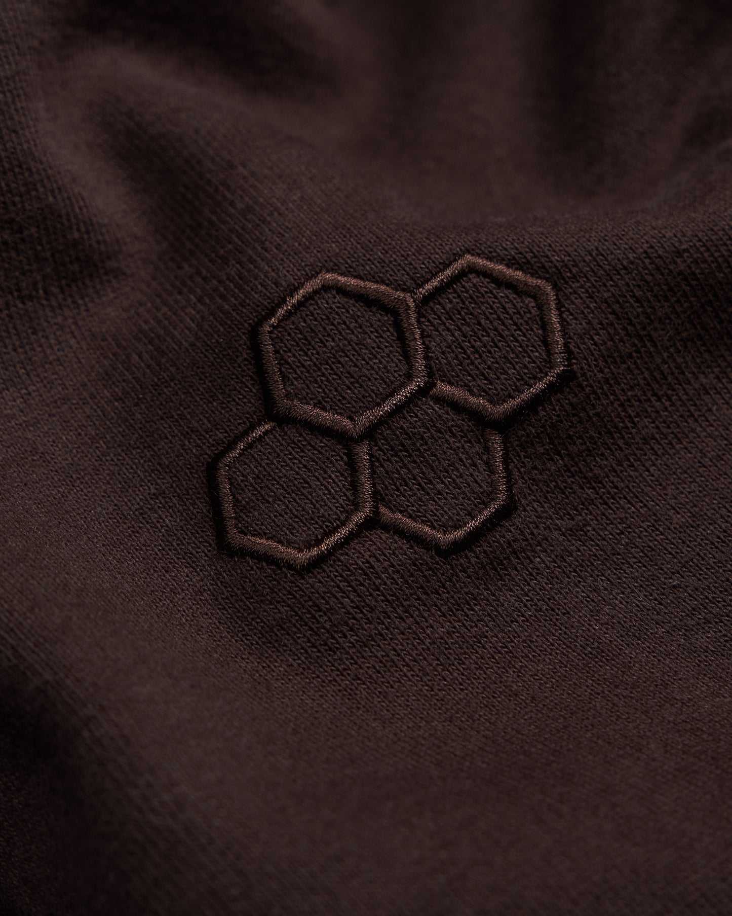 Close-up of a brown fabric with an embroidered hexagonal pattern.