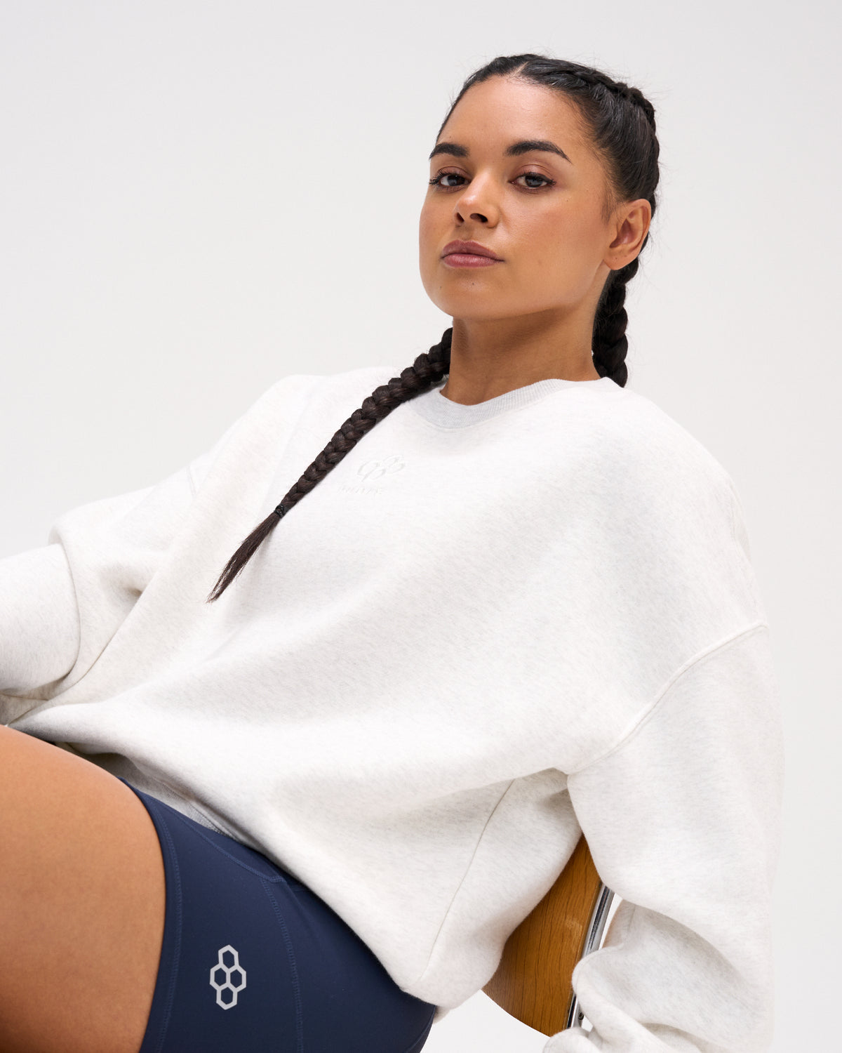 Woman wearing the RUDIS Hex Relaxed Comfort Fleece Crewneck in Heather Silver with a subtle chest logo, dropped shoulders, and ribbed neckline.
Copy alt text